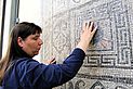 tastende Hände auf eines mosaikbezierten "Teppichs"