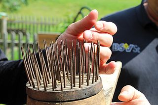 Bildtext: tastende Händer auf der "Riffel" für die Gewinnung der Flachsfäden/Leinfäden.
